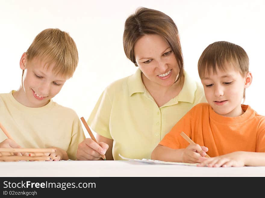 Young mother sitting at the table and draws with his sons. Young mother sitting at the table and draws with his sons