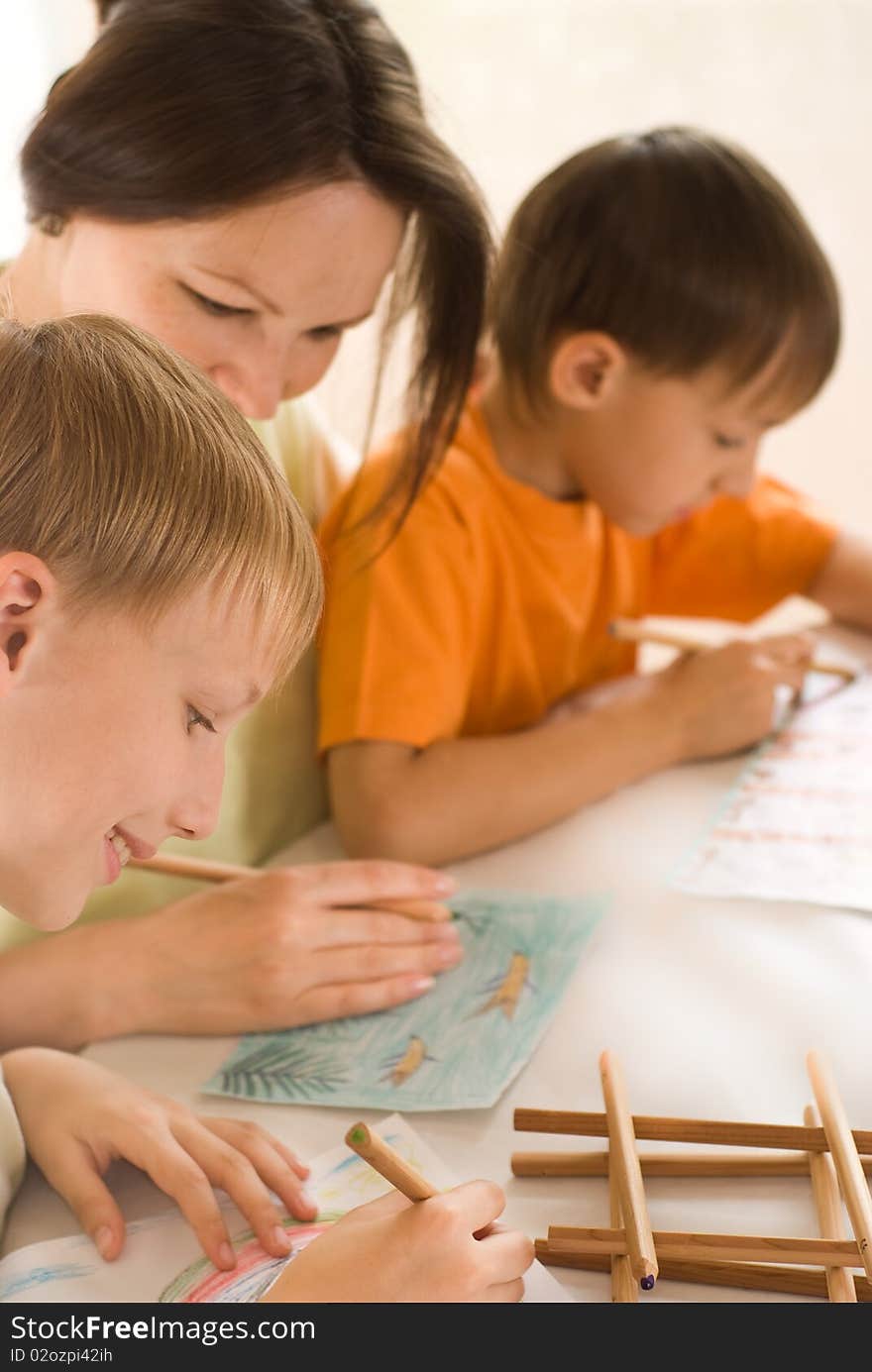 Young mother drawing at the table with her sons. Young mother drawing at the table with her sons