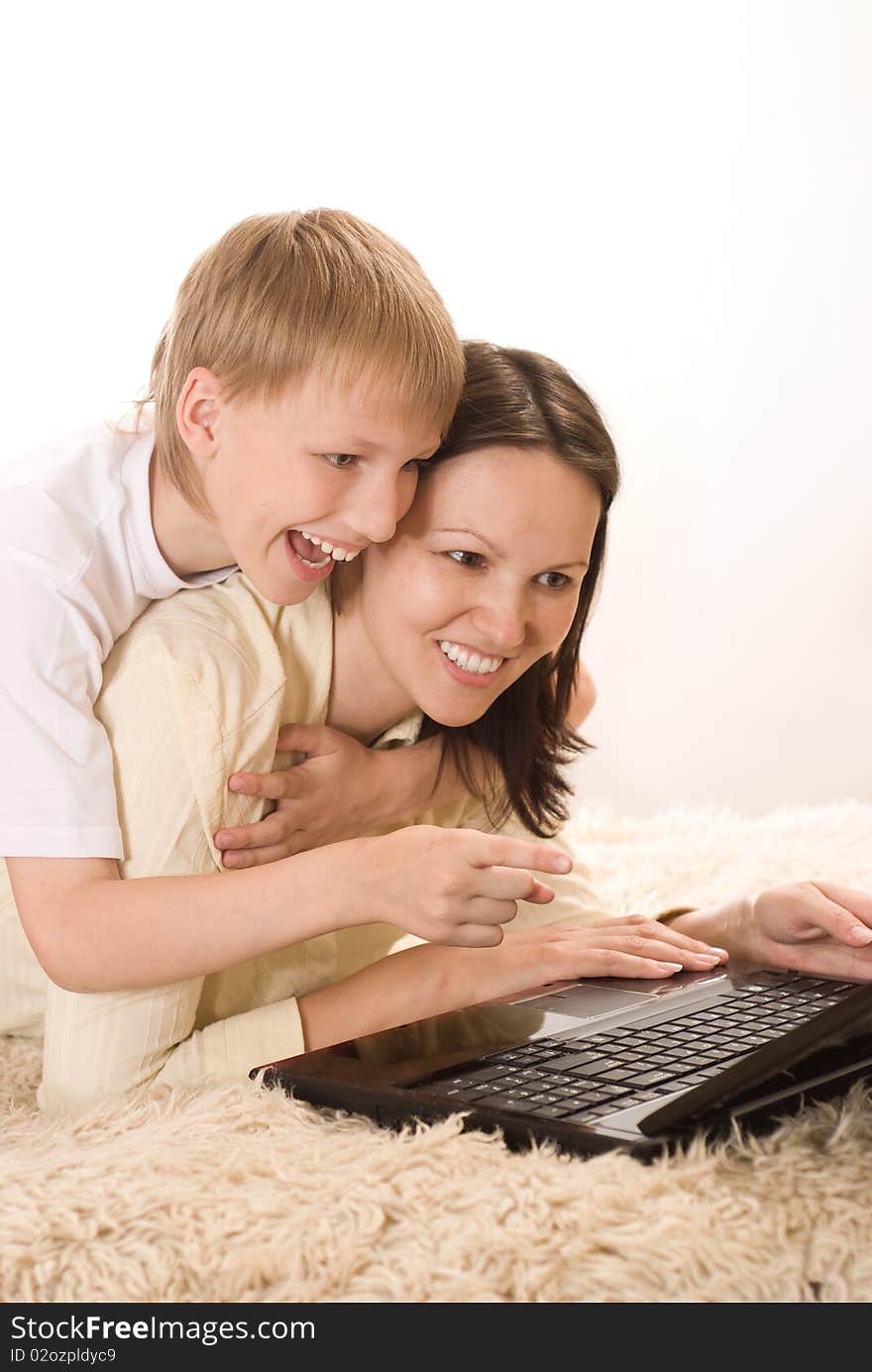 Happy mom and son lying with laptop