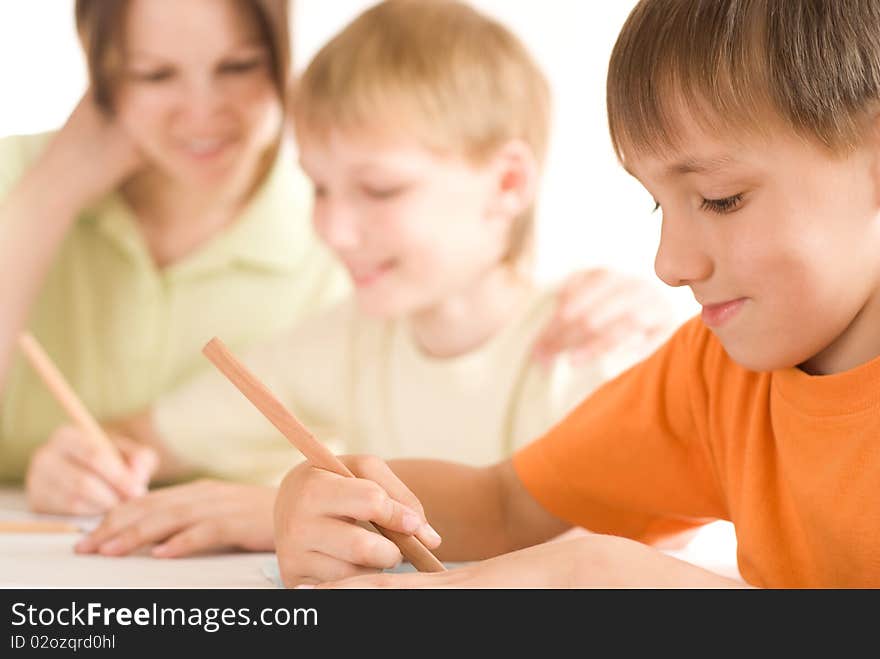 Mother sitting at the table and draws with his sons. Mother sitting at the table and draws with his sons