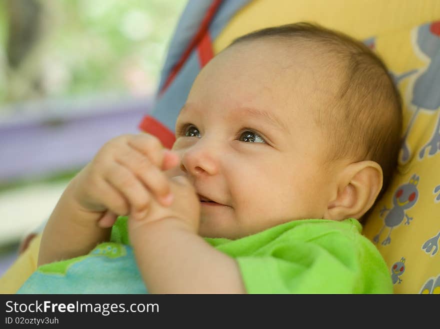 Happy newborn baby lies on a green background