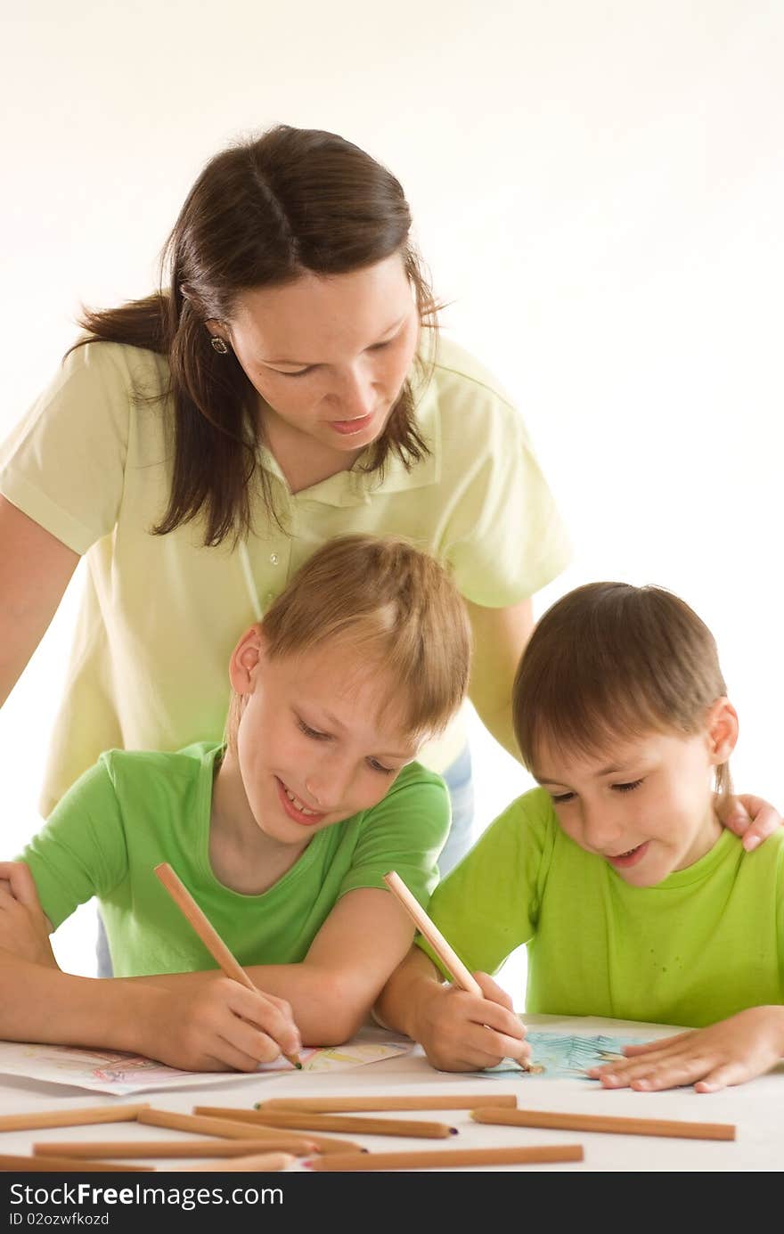 Mother staying at the table and draws with his sons. Mother staying at the table and draws with his sons