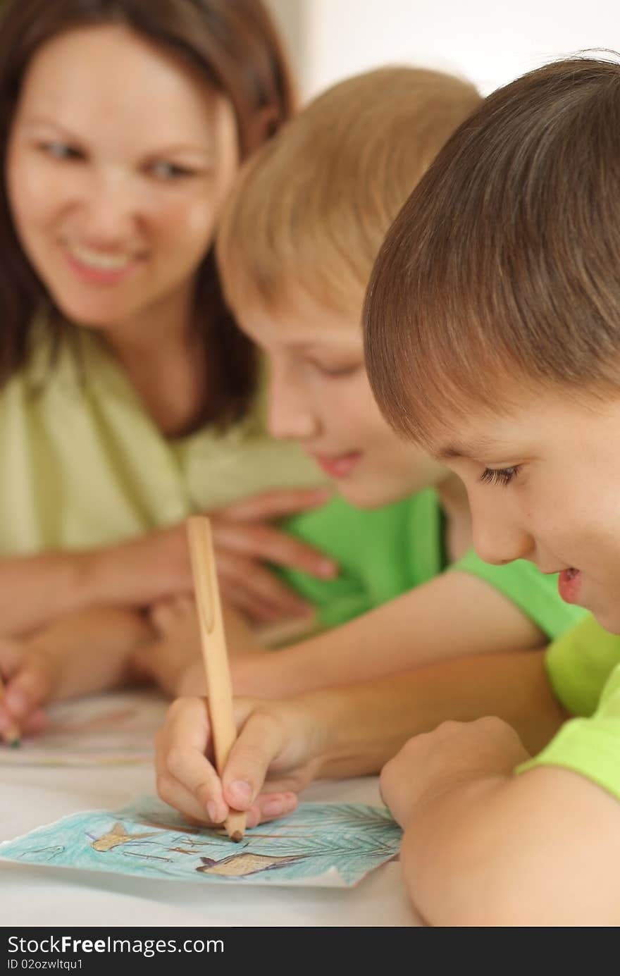 Mother at the table and draws with his sons. Mother at the table and draws with his sons