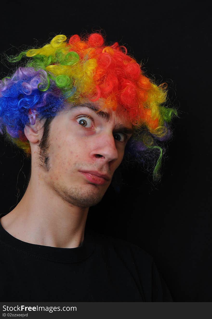 A silly crazy man wearing a clown wig with rainbow colors staring at the camera with a serious look. A silly crazy man wearing a clown wig with rainbow colors staring at the camera with a serious look.