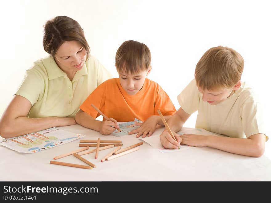 Young mother sitting at the table and draws with his sons. Young mother sitting at the table and draws with his sons