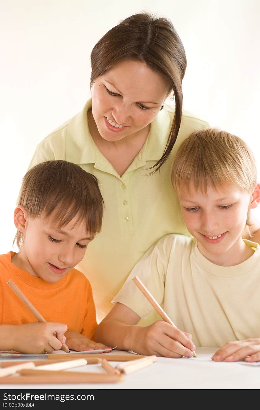 Young mother sitting at the table and draws with sons. Young mother sitting at the table and draws with sons