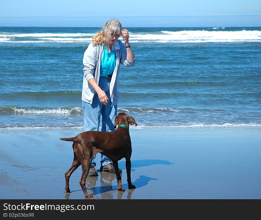 An active senior woman playing with her dog at Long Beach Washington