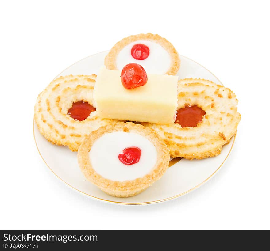 Coconut and jam biscuits with slice of cake and cherry on top. Isolated over white background. Coconut and jam biscuits with slice of cake and cherry on top. Isolated over white background.