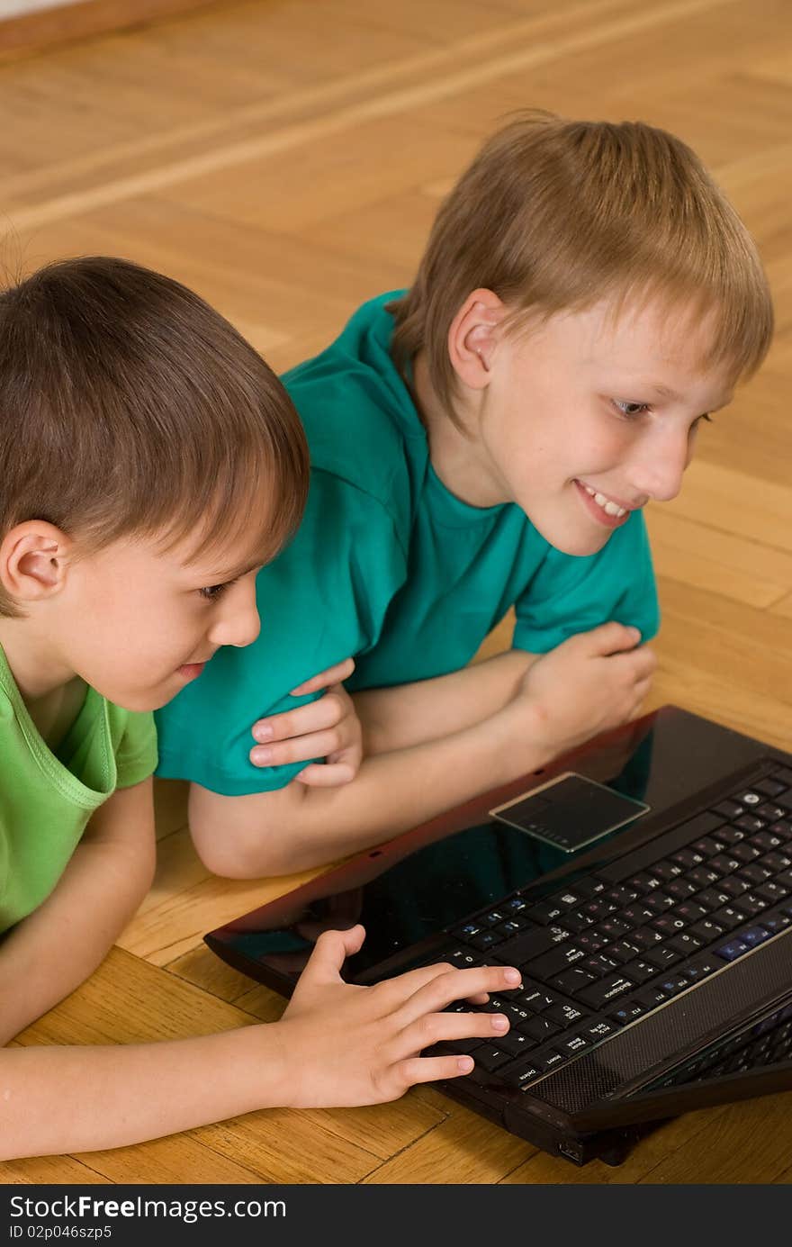 Two little brothers lie with laptop