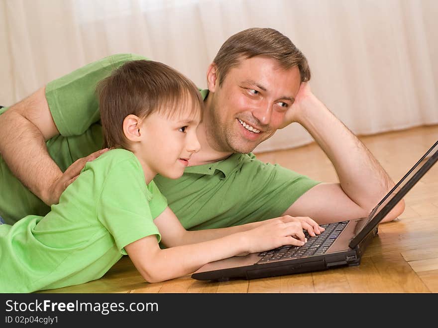 Father and son lying on the carpet with laptop. Father and son lying on the carpet with laptop