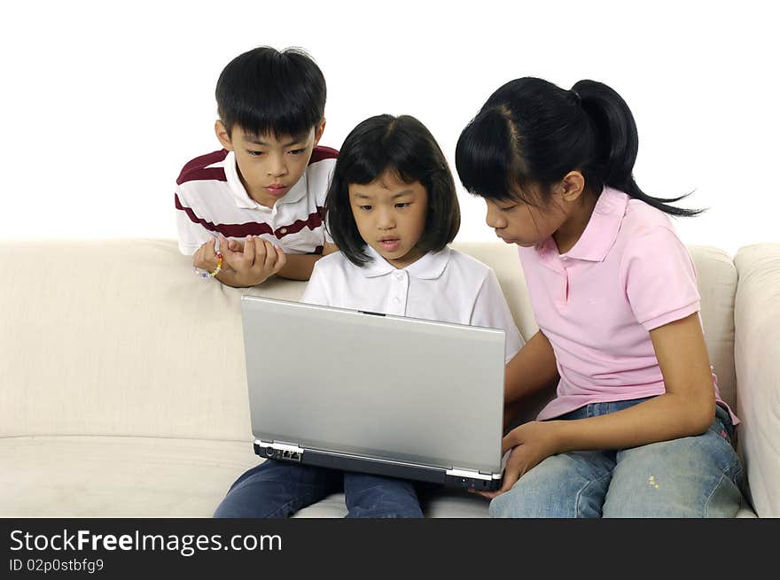 Young brother and sister sitting on couch at home, browsing internet on laptop computer. Young brother and sister sitting on couch at home, browsing internet on laptop computer