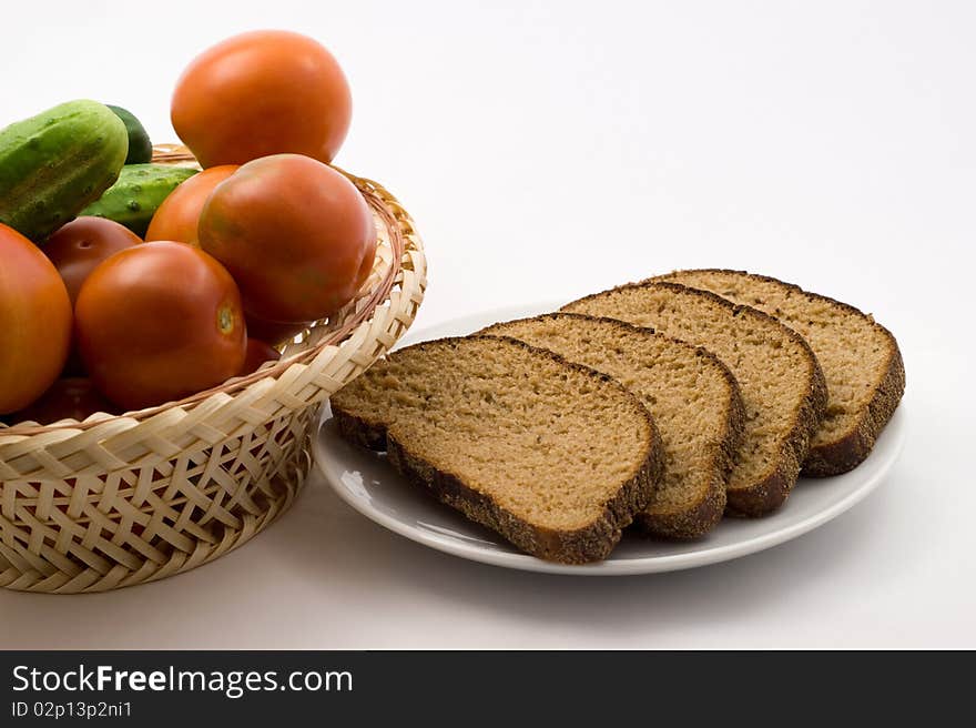 Tomatoes and cucumbers in a plate of rice straw and bread on a plate on a white background. Tomatoes and cucumbers in a plate of rice straw and bread on a plate on a white background