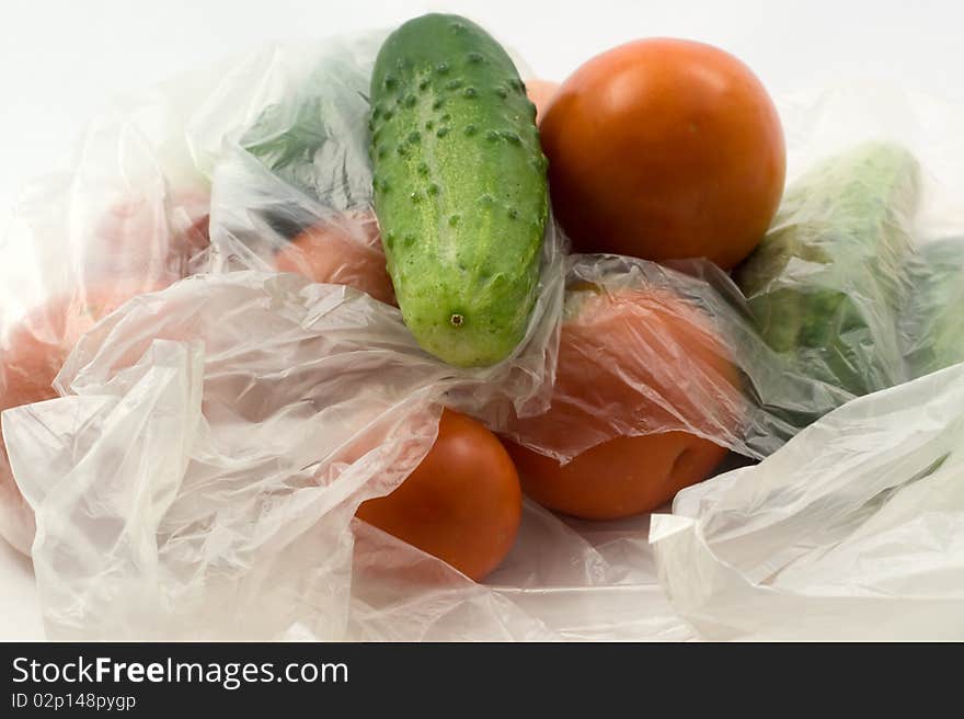 Tomatoes and cucumbers in PE on a white background