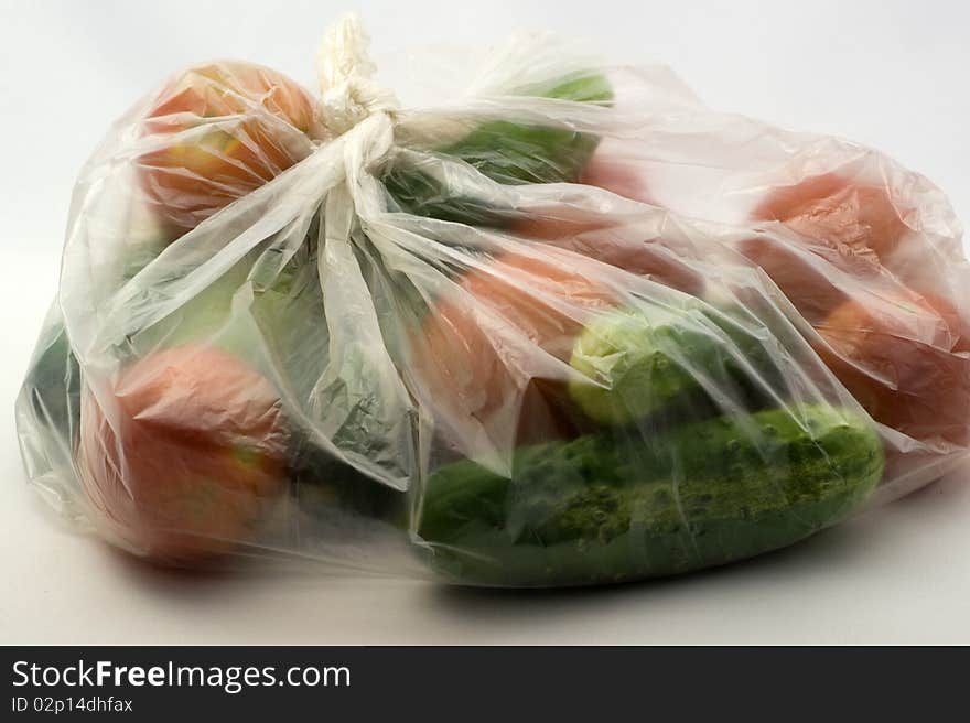 Tomatoes and cucumbers in PE on a white background