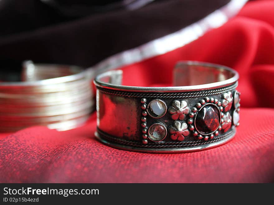 An ornate silver bracelet on a red silk background. An ornate silver bracelet on a red silk background