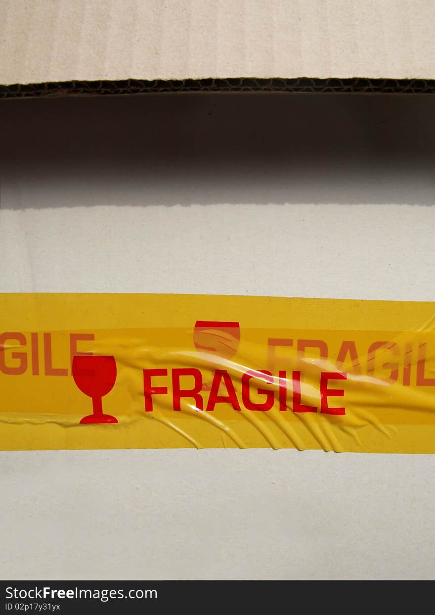 A corrugated cardboard box with a yellow tape fragile label. A corrugated cardboard box with a yellow tape fragile label