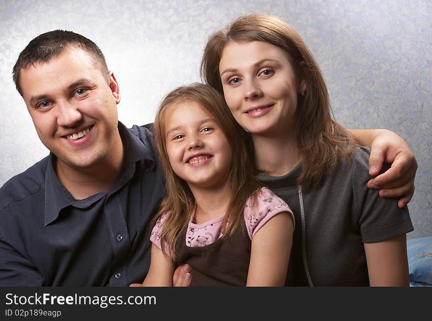 Young mother, father, and daughter over light defocused background. Young mother, father, and daughter over light defocused background