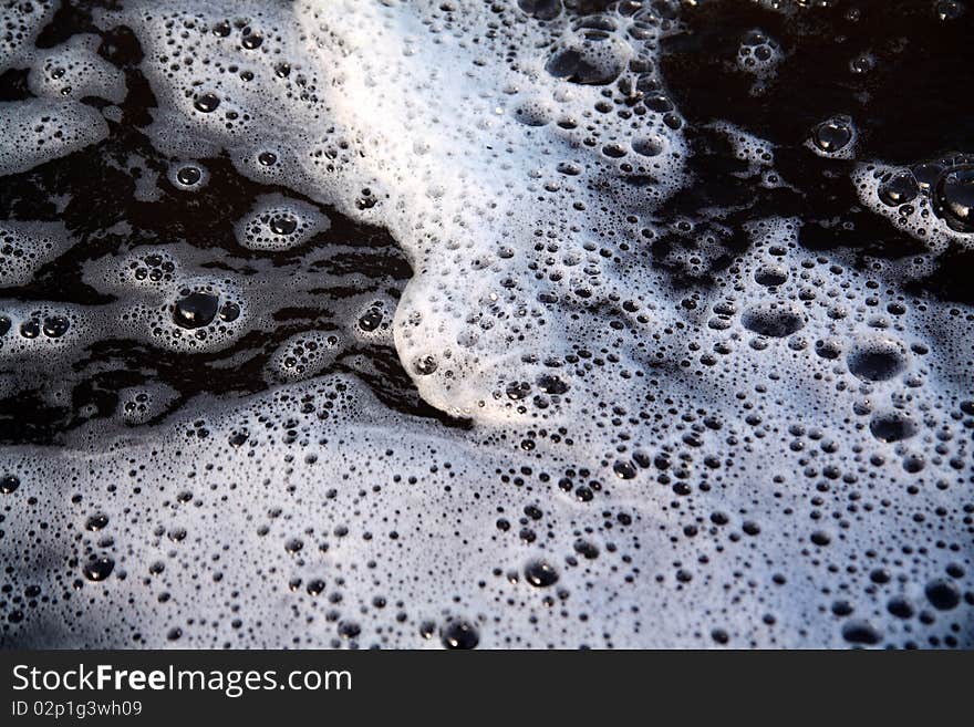 White spume on black surface water