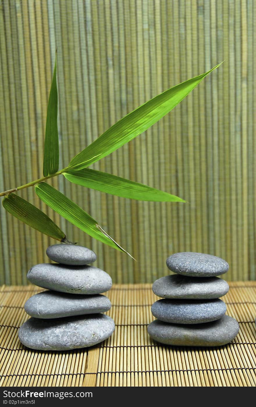 Bamboo leaf and a stack of stones on a bamboo mat. Bamboo leaf and a stack of stones on a bamboo mat