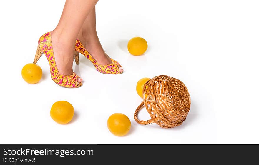 Woman feet in fashion shoes and oranges with basket isolated on white. Woman feet in fashion shoes and oranges with basket isolated on white