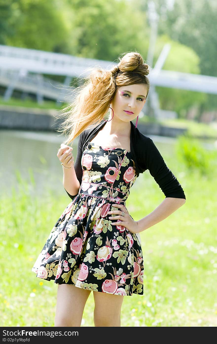 Teenager girl model presenting clothes in the park near the water and a bridge