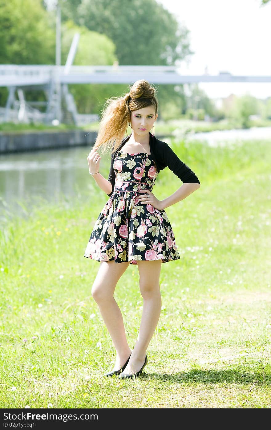 Teenager girl model presenting clothes in the park near the water and a bridge