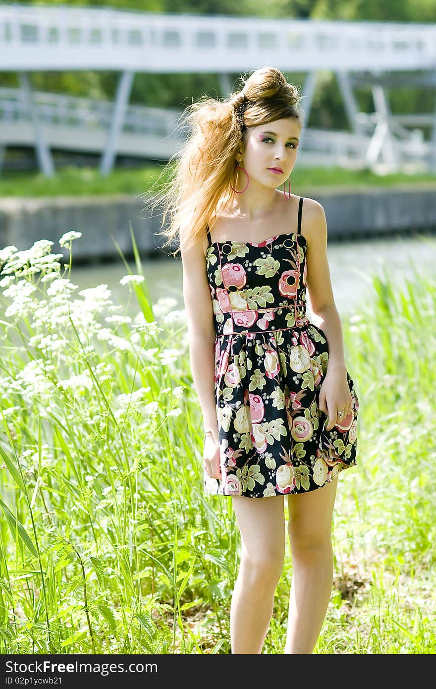 Teenager girl model presenting clothes in the park near the water and a bridge