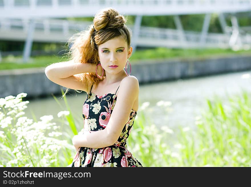 Teenager girl model presenting clothes in the park near the water and a bridge