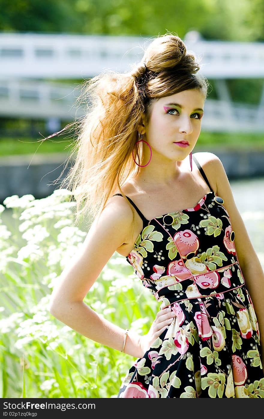 Teenager girl model presenting clothes in the park near the water and a bridge