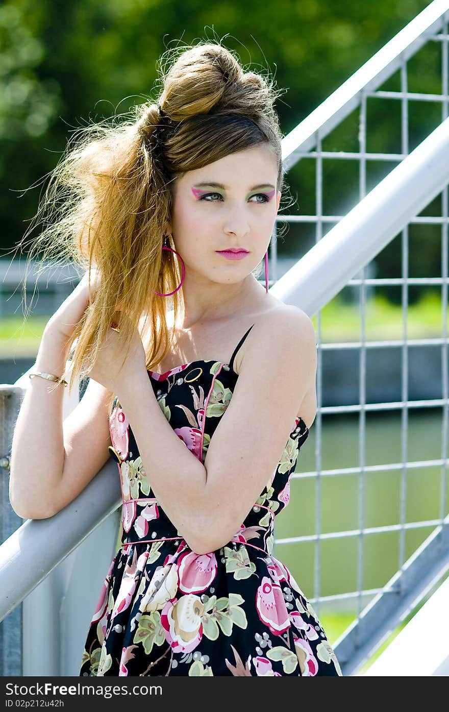 Teenager girl model presenting clothes in the park near the water and a bridge