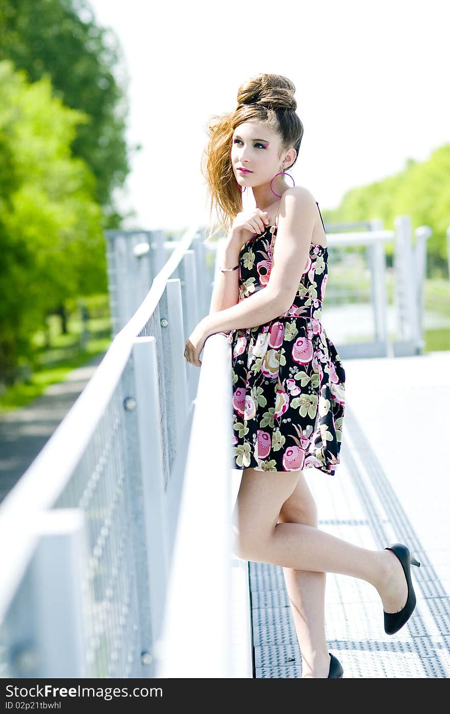 Teenager girl model presenting clothes in the park near the water and a bridge