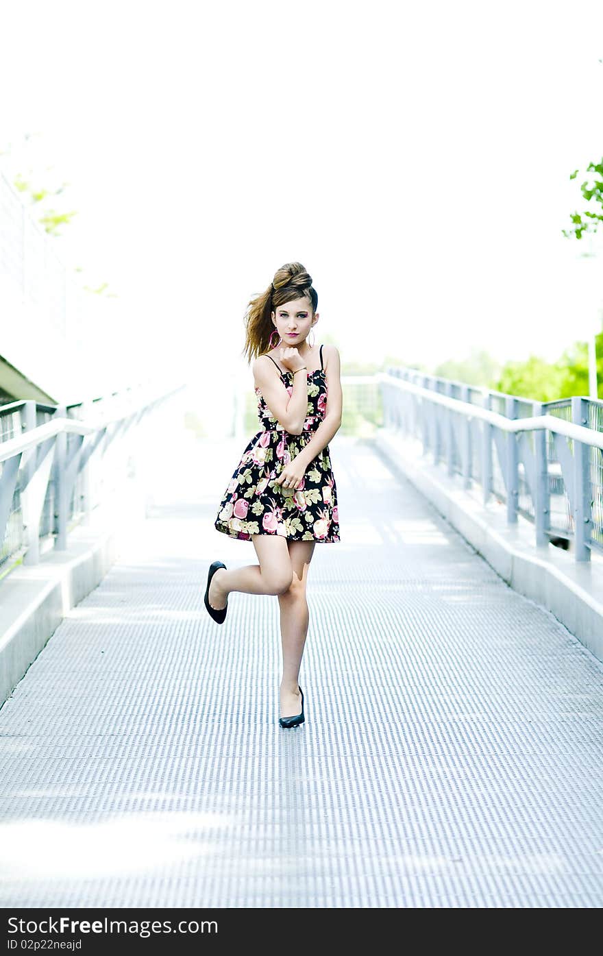 Teenager girl model presenting clothes on a bridge in the parc, light natural background