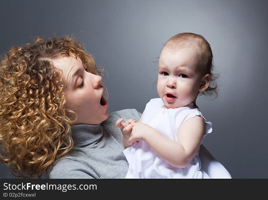 Young beautiful curly mother holding cute upset baby