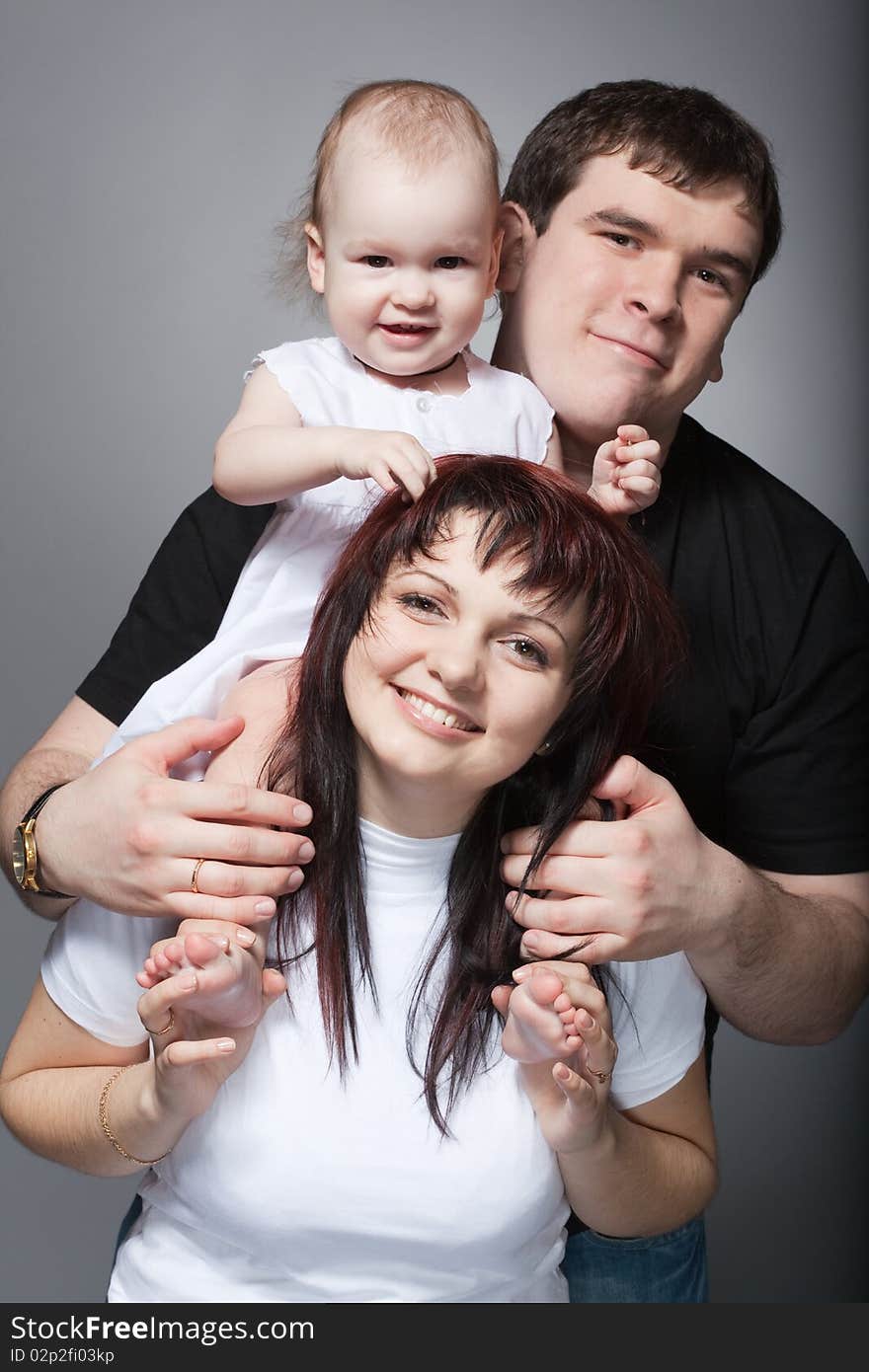 Closeup family portrait of young loving couple with cute baby on mother's shoulders. Closeup family portrait of young loving couple with cute baby on mother's shoulders