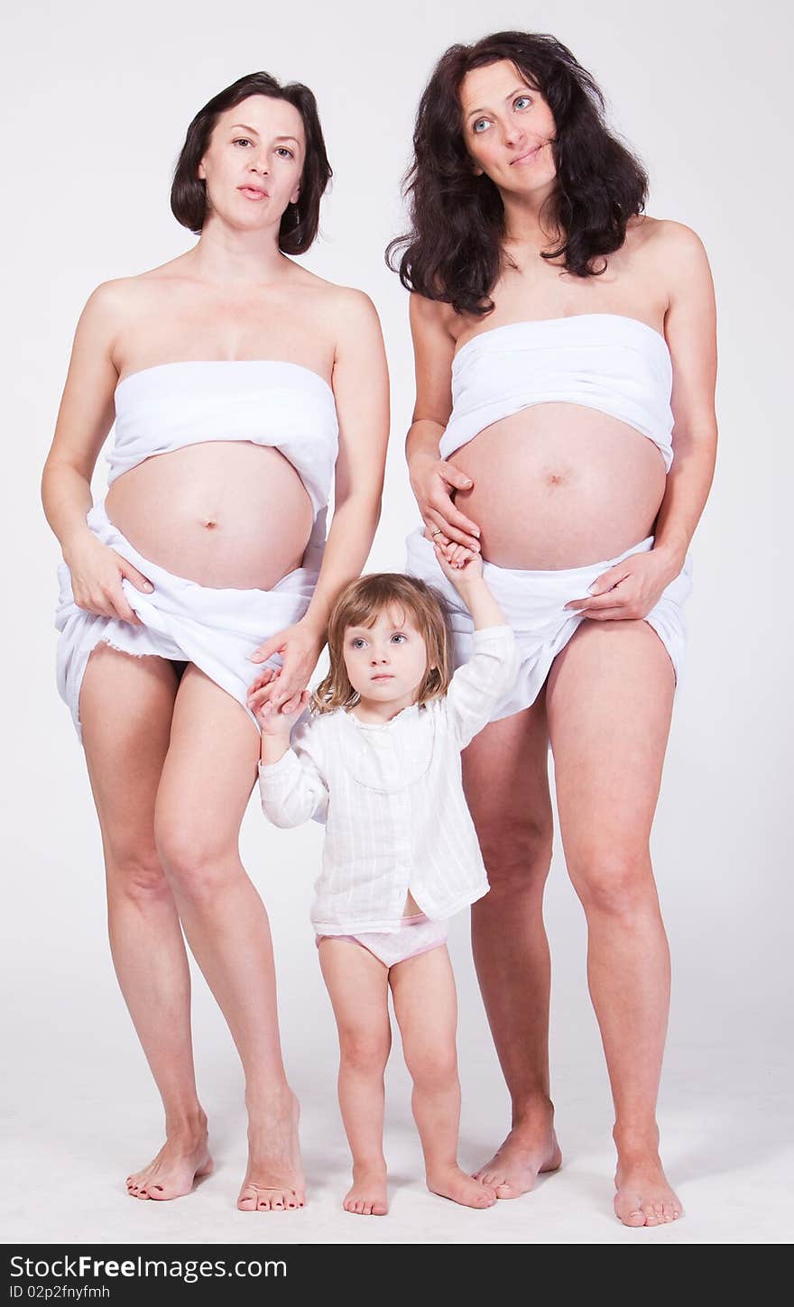 Studio portrait of two happy pregnant women keep the cute child arm