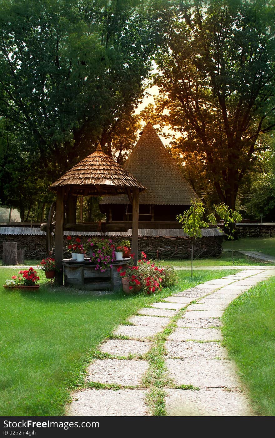 Nice scenery with grass, flowers old houses and a fountain well. The road is taking you to a beautiful journey. Nice scenery with grass, flowers old houses and a fountain well. The road is taking you to a beautiful journey