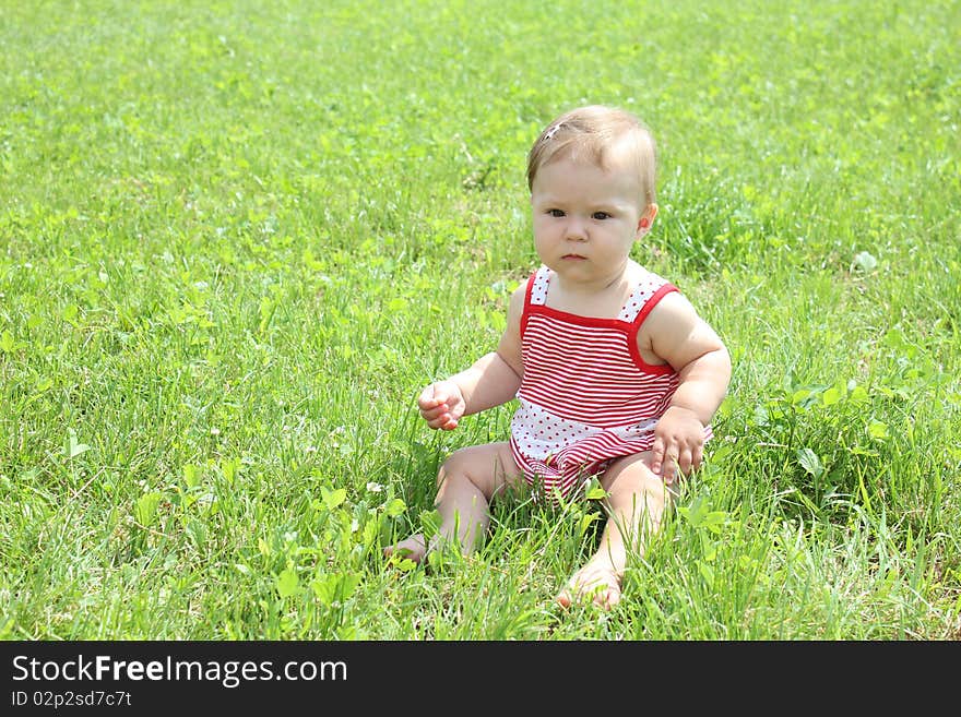 Child is sitting on the green grass