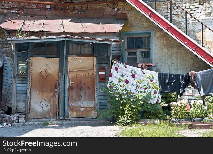 Fragment of the old court. Rickety porch and door with the mailboxes. Near the entrance to the house drying clothes. Urban fragment of the Russian provinces