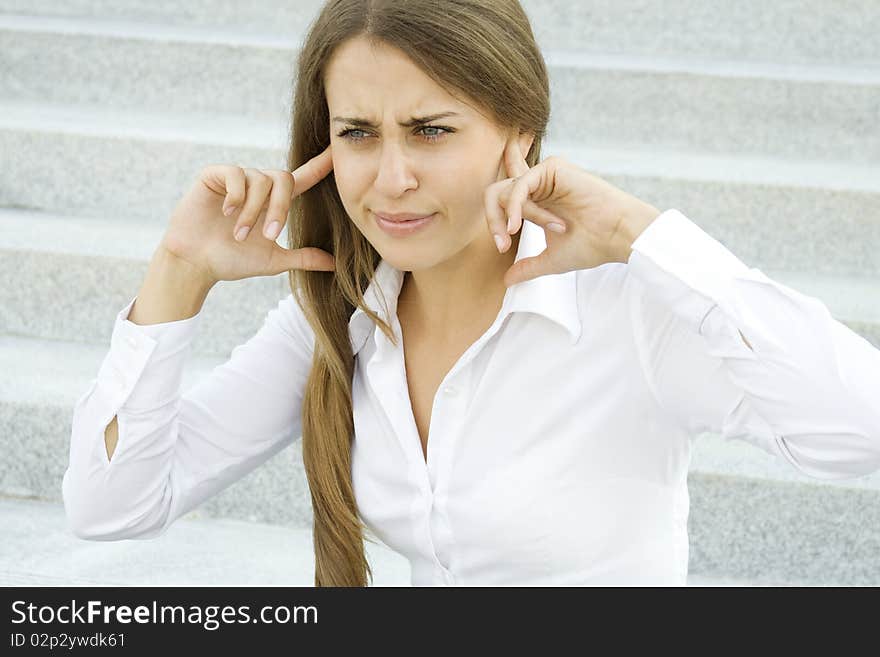 Young business woman plugs fingers in their ears. Young business woman plugs fingers in their ears