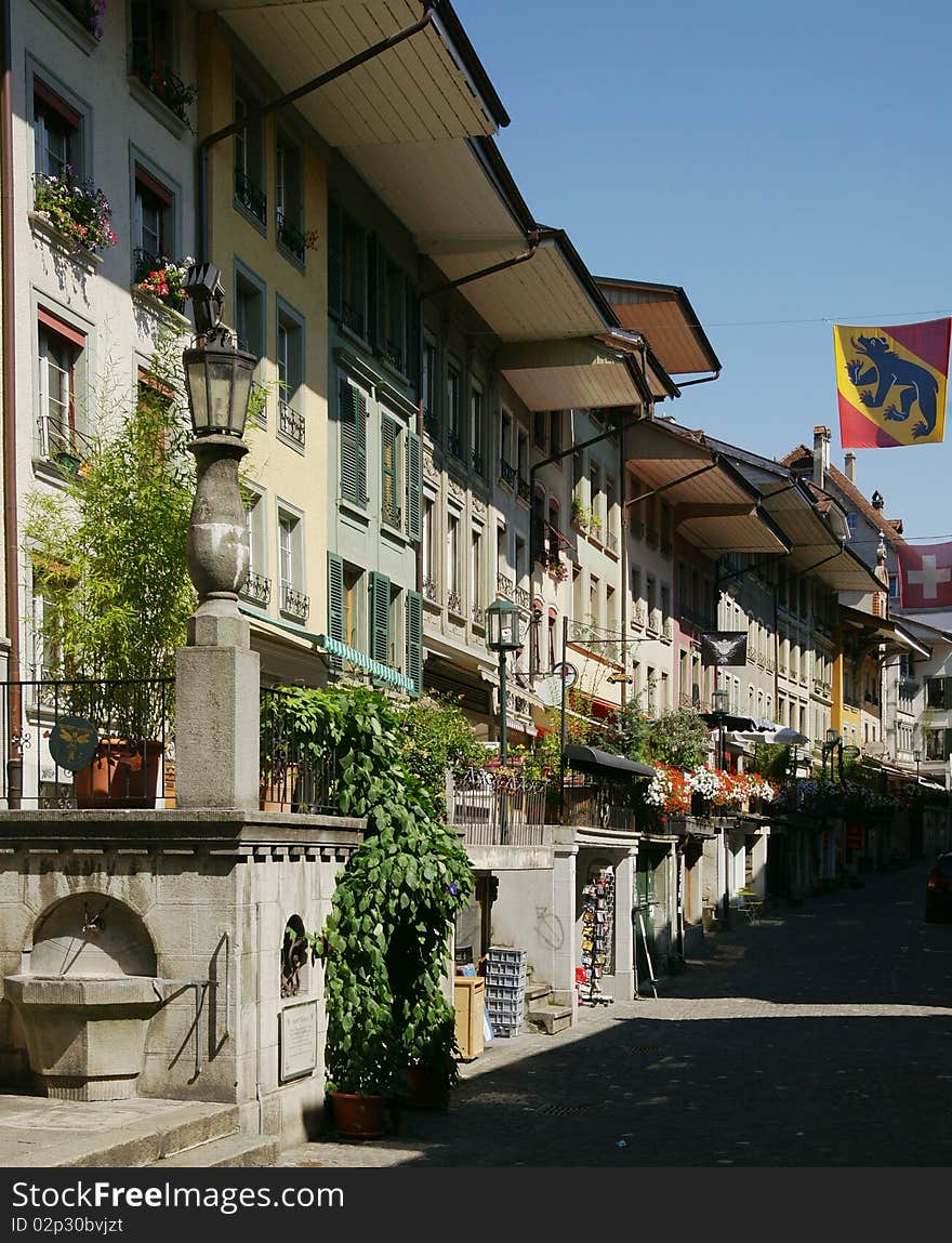 A street scene in the Swiss town of Thun on the Aare River. The town is located in the Berne county the flag of which is being displayed on the right.