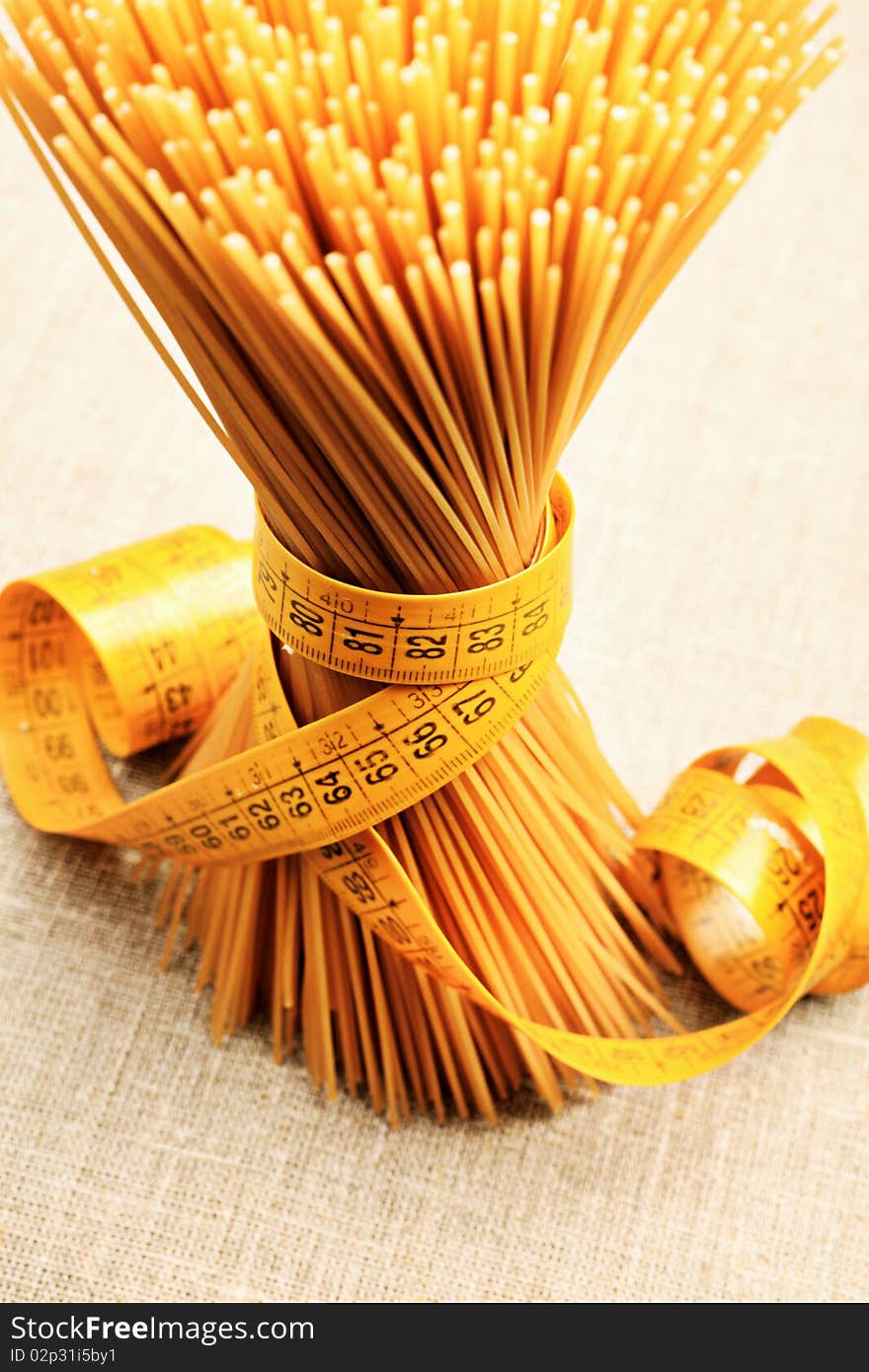 Food concept: bunch of uncooked spaghetti tied with tape measure. Food concept: bunch of uncooked spaghetti tied with tape measure.