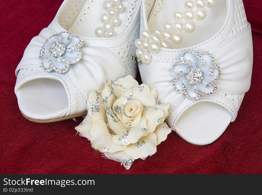 Beautiful wedding shoes with pearls and flower on red background