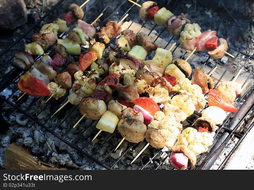 Pieces of meat and vegetables getting done on the grill. Pieces of meat and vegetables getting done on the grill