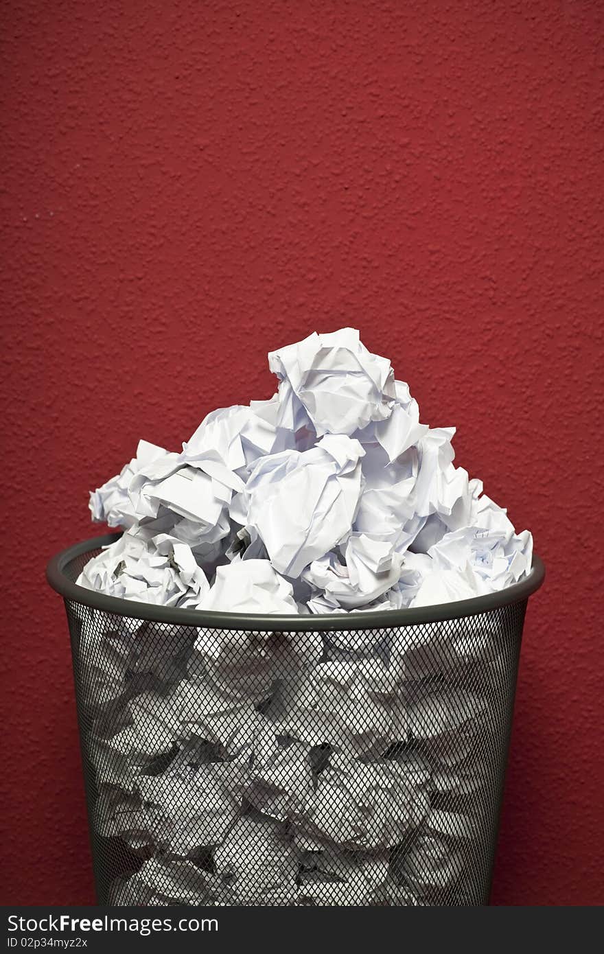 Trashcan in front of red office wall filled with rumpled paper. Trashcan in front of red office wall filled with rumpled paper