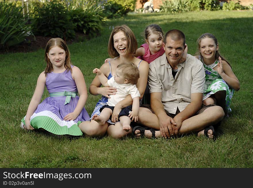 Young family on the grass at the backyard. Young family on the grass at the backyard.