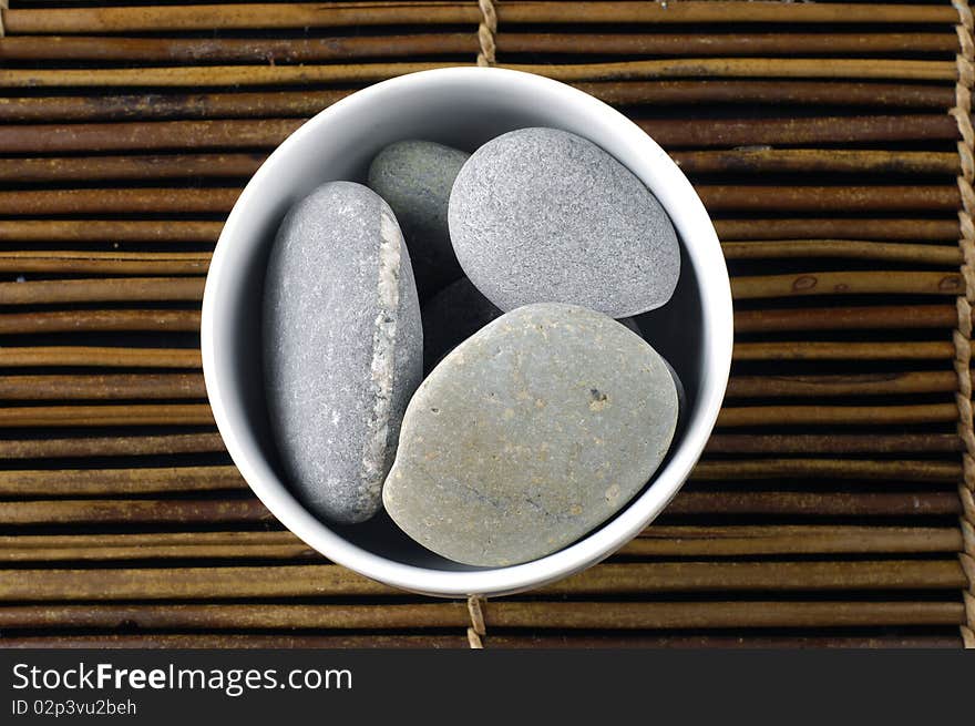 Zen stones in a bowl on bamboo mat. Zen stones in a bowl on bamboo mat