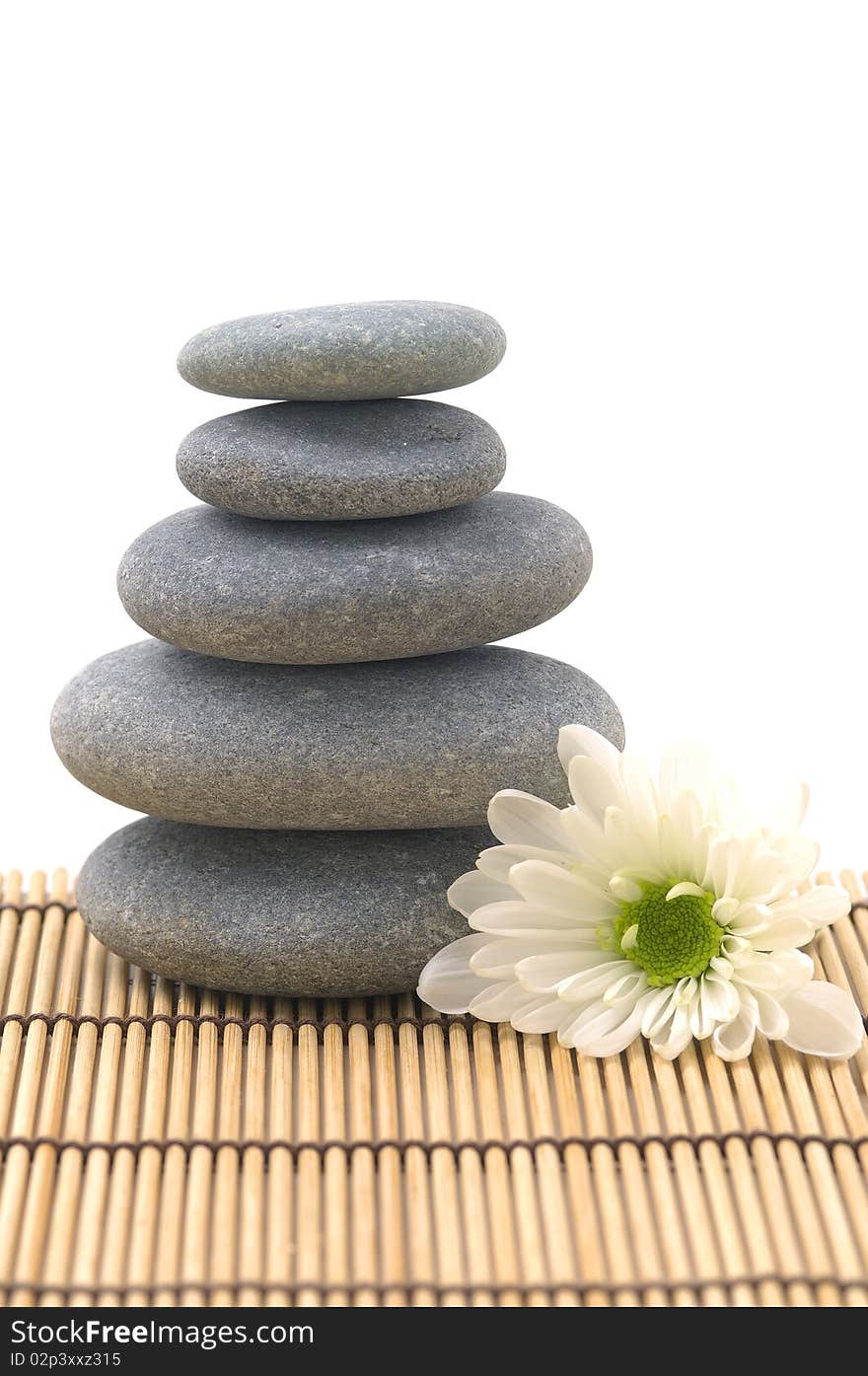 White flower with stack of pebbles on mat. White flower with stack of pebbles on mat