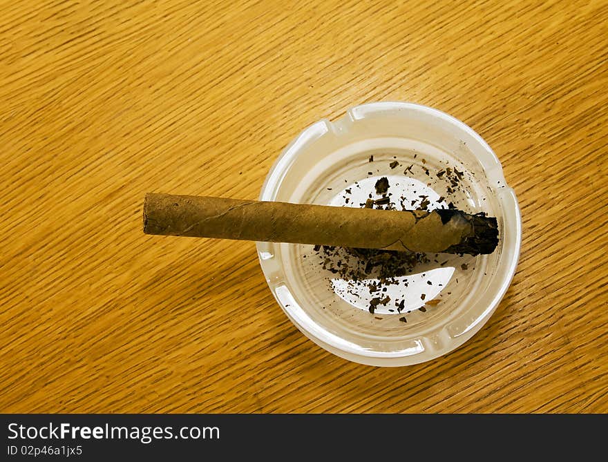 Cigar which only have set fire, lying in a white ashtray. Cigar which only have set fire, lying in a white ashtray