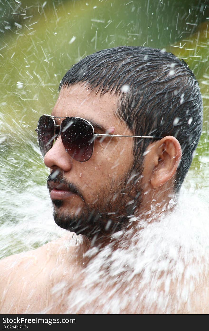 Close up of a man bathing under a waterfall