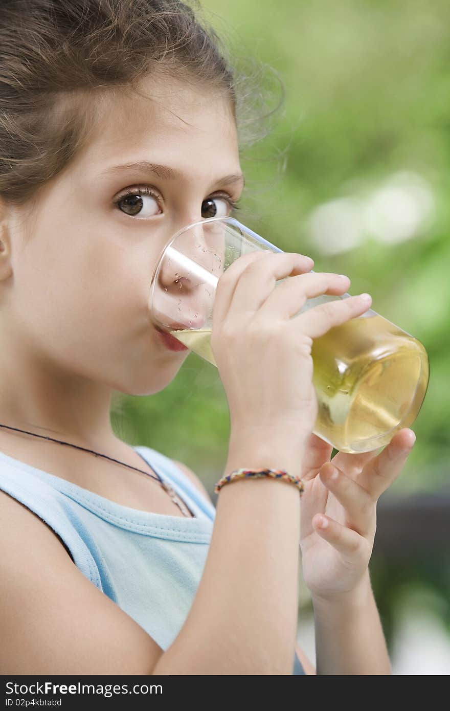 Portrait of nice little girl drinking juice in summer environment